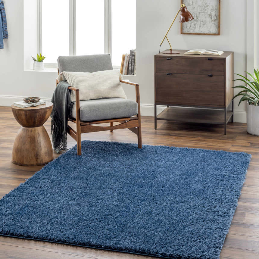 Living room scene with Faina Solid Dark Blue Shag rug, gray chair, wood side table, and mid-century modern dresser. Roomscene-Rectangle