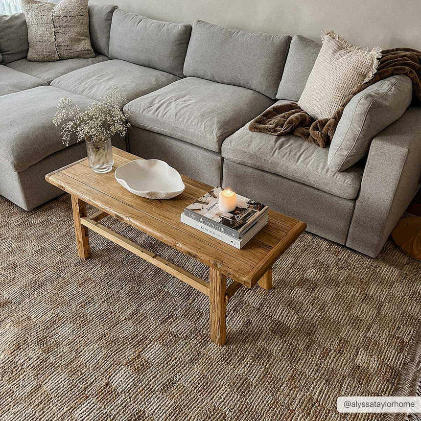 Living room scene with a gray sectional, wood bench, and Ionut Checkered Jute Area Rug in beige and tan. Farmhouse style. Roomscene-Rectangle