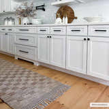 Farmhouse kitchen with white cabinets and Ionut Checkered Jute Area Rug in beige and tan on wood floor. Roomscene-Runner
