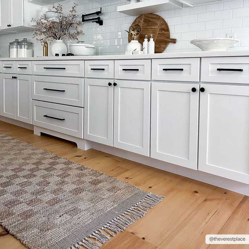 Farmhouse kitchen with white cabinets and Ionut Checkered Jute Area Rug in beige and tan on wood floor. Roomscene-Runner