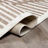 Close-up of the Anah Cream Outdoor Rug featuring a geometric bone and nutmeg pattern and machine-woven texture. Fold