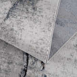 Close-up of the Fremantle Gray Marble Rug showing its cream, light gray, and dark gray abstract pattern and woven backing. Fold