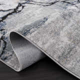 Close-up of the Fremantle Gray Marble Rug showing its cream, gray, gold, and blue contemporary pattern and machine-woven texture. Fold