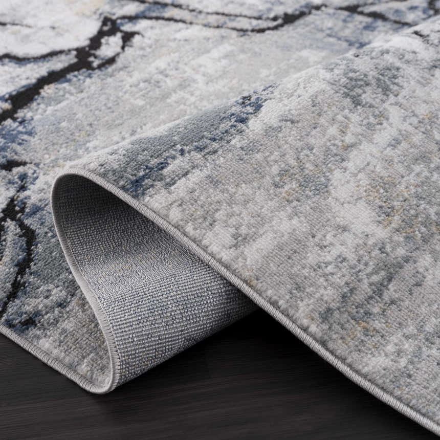 Close-up of the Fremantle Gray Marble Rug showing its cream, gray, gold, and blue contemporary pattern and machine-woven texture. Fold