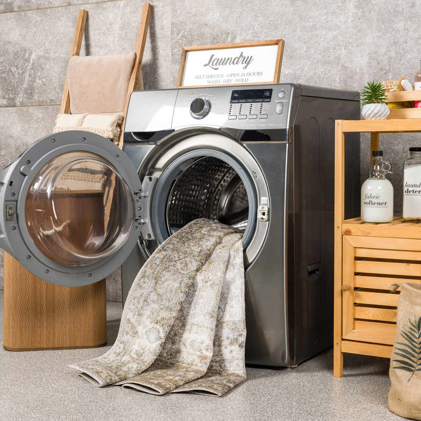 Laundry room scene with a light blue, olive, tan, and yellow Gael Boutique Washable Rug in the washing machine. Washing-Machine