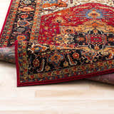 Close-up of the Malpas Area Rug showing its black, burgundy, and ivory traditional pattern and machine-woven texture. Fold
