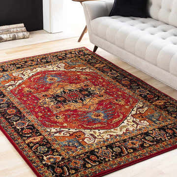 Living room scene with a red, black, and orange Oriental style Malpas Area Rug under a light gray sofa. Roomscene-Rectangle