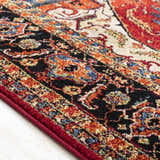 Close-up of the Malpas Area Rug showing its black, burgundy, orange, and ivory traditional pattern and texture. Texture