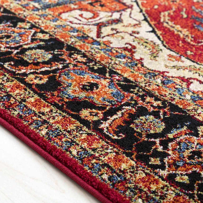 Close-up of the Malpas Area Rug showing its black, burgundy, orange, and ivory traditional pattern and texture. Texture
