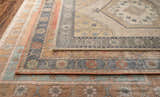 Close-up of the hand-tufted Duckenfield Area Rug showing its floral, geometric, and traditional rug patterns. Wool rug in tan, orange, and gray. Styleshot