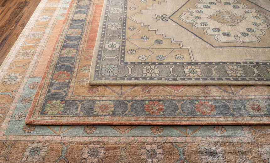 Close-up of the hand-tufted Duckenfield Area Rug showing its floral, geometric, and traditional rug patterns. Wool rug in tan, orange, and gray. Styleshot