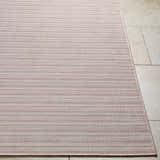 Close-up of Greg Pink Area Rug showing horizontal stripes and woven texture on a beige tile floor. Front