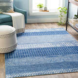 Living room scene with denim and ivory Nampa Area Rug, blue armchair, and neutral ottoman on wood floor. Roomscene-Rectangle