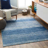 Living room scene with a blue and ivory Nampa Area Rug, gray chair, and mid-century modern cabinet. Roomscene-Rectangle