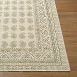 Close-up of Alo Nabela Noor Home x LIVABLISS NBAL-2302 Area Rug. Green paisley pattern on off-white jute blend, on wood floor. Front