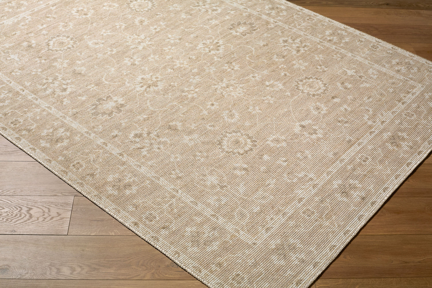 Close-up of the Asha Machine Woven Nabela Noor Home x LIVABLISS NBAS-2300 Area Rug. Neutral rug with traditional floral pattern. Corner