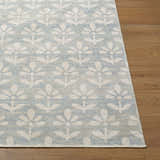 Close-up of Maya Nabela Noor Home x LIVABLISS NBMY-2301 area rug with sky blue and off-white floral pattern on wood floor. Front