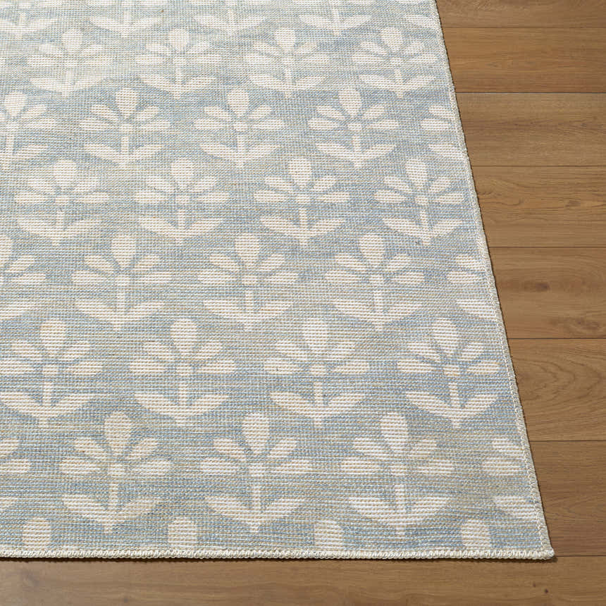 Close-up of Maya Nabela Noor Home x LIVABLISS NBMY-2301 area rug with sky blue and off-white floral pattern on wood floor. Front