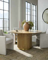 Dining room scene with a Becki Owens x Livabliss Renaissance Area Rug in beige, olive, and tan under a round table and modern chairs. Styleshot