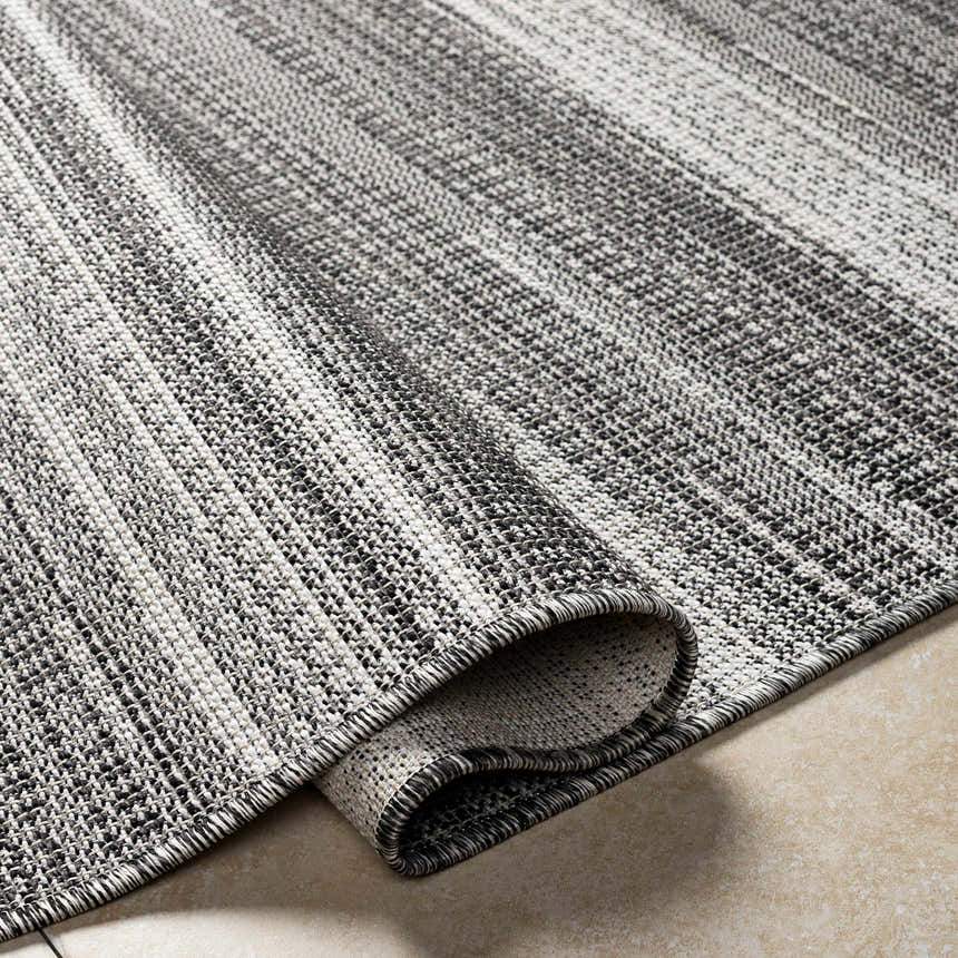 Close-up of the Kris Black Area Rug showing the beachhouse and dark gray woven texture and rolled edge. Fold