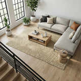 Living room scene with a beige Kanuha Washable Area Rug, light gray sectional sofa, wood coffee table, and indoor plants. Roomscene-Rectangle