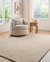 Light-filled living room with a beige Lnahhe Abstract Modern wool rug, round chair, and wooden side table. Roomscene-Rectangle