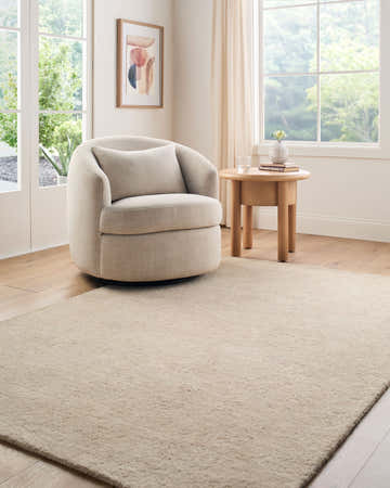 Light-filled living room with a beige Lnahhe Abstract Modern wool rug, round chair, and wooden side table. Roomscene-Rectangle