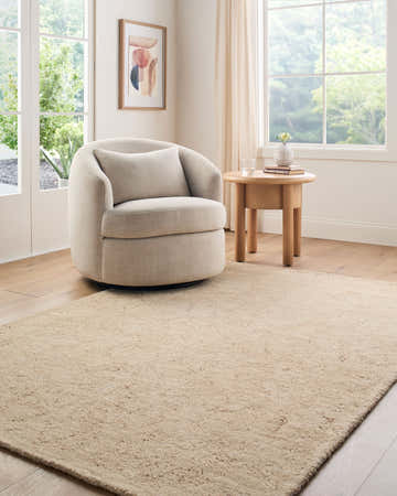 Light-filled living room with a beige swivel chair and the Nipo Beige Abstract Area Rug on hardwood floors. Roomscene-Rectangle