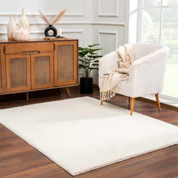 Living room scene with Crevalo Cream rug, wood cabinet, and cozy white armchair near a bright window. Roomscene-Rectangle