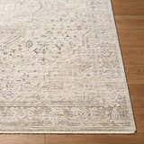 Close-up of the beige and charcoal Dalila Area Rug showing traditional pattern and fringe detail on hardwood floor. Front