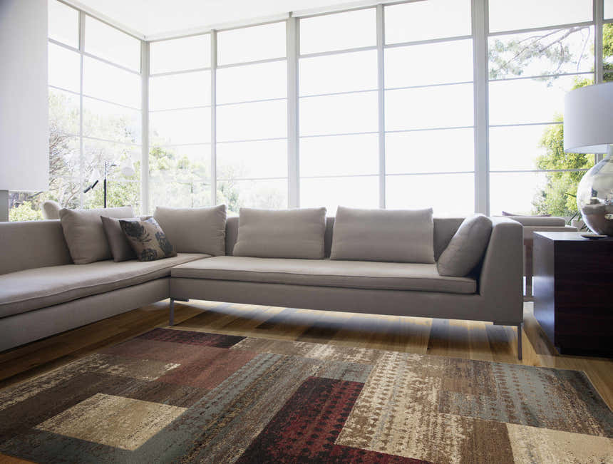 Bright living room with a gray sofa and the Sentinel Riley Geometric Rug in shades of brown, red, and gray. Roomscene-Rectangle