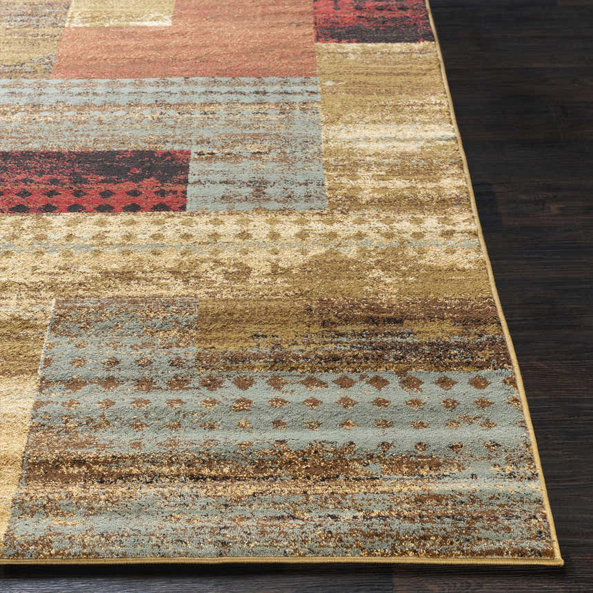 Close-up of the Sentinel Riley Geometric Rug. Features black, red, brown, green, and mustard hues in a contemporary pattern. Front