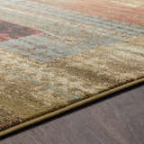 Close-up of the Sentinel Riley Geometric Rug, showing its texture, geometric pattern, and colors like green, brown, red, and blue. Texture