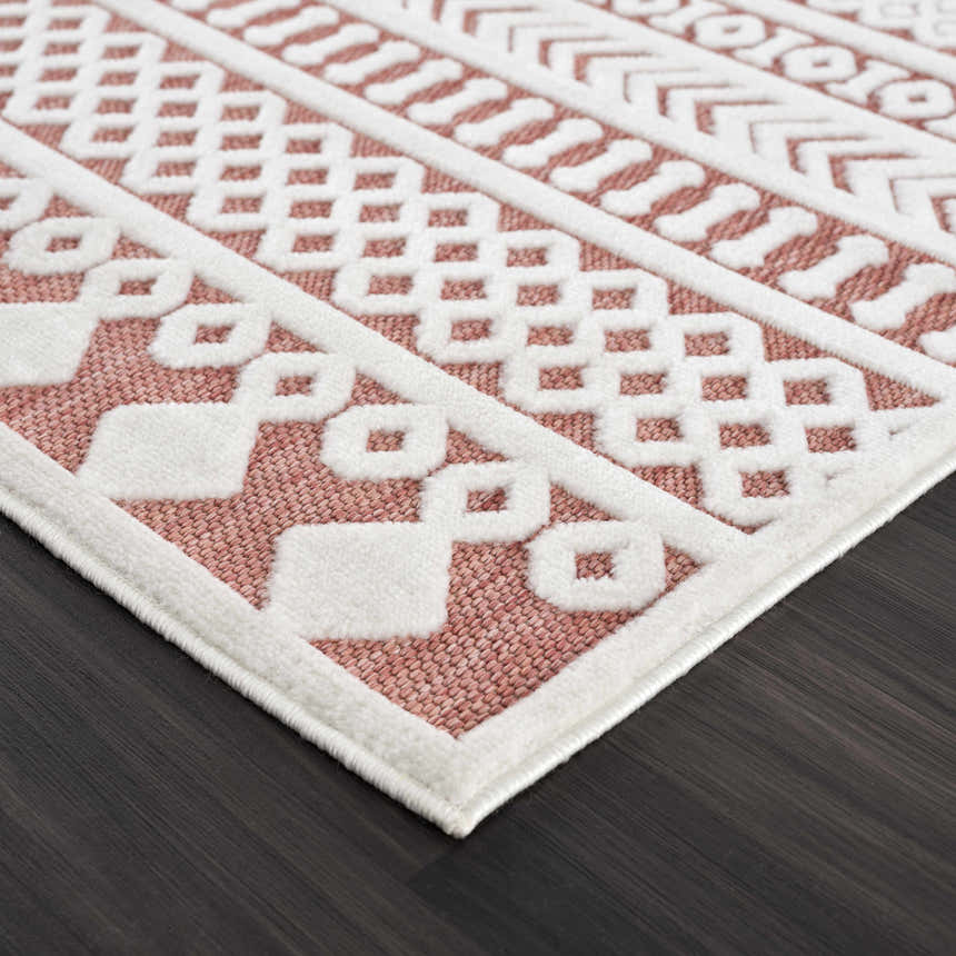Close up of the Jove Orange Outdoor Rug showing the bone geometric pattern and terracotta color. Corner