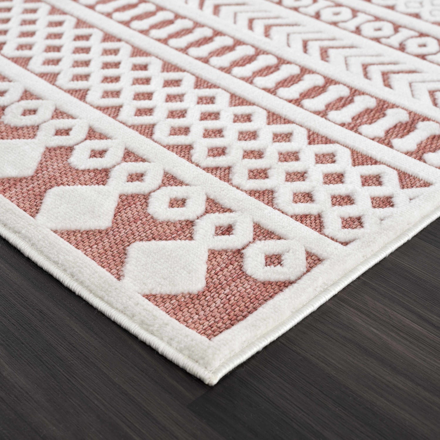 Close up of the Jove Orange Outdoor Rug showing the bone geometric pattern and terracotta color. Corner