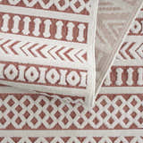 Close up of the Jove Orange Outdoor Rug showing the bone and terracotta geometric Southwestern pattern. Fold
