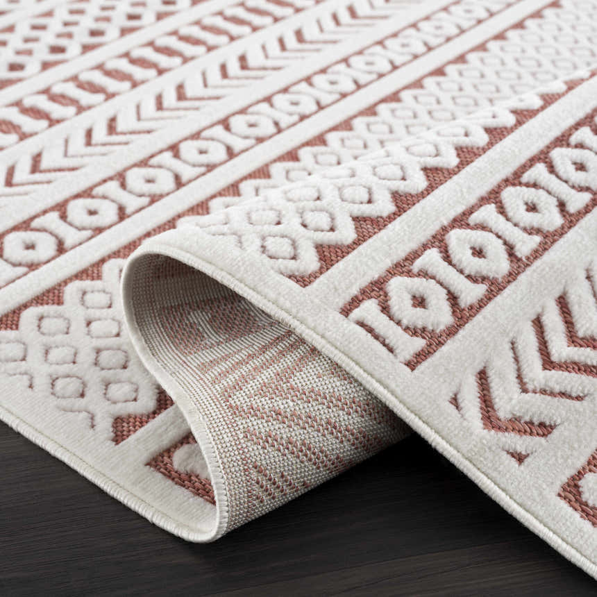Close-up of the Jove Orange Outdoor Rug showing its bone and terracotta Southwestern-style geometric pattern and woven texture. Fold
