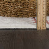 Close-up of the Jove Orange Outdoor Rug showing the pile height with a ruler, plus bone and clay colors. Pile