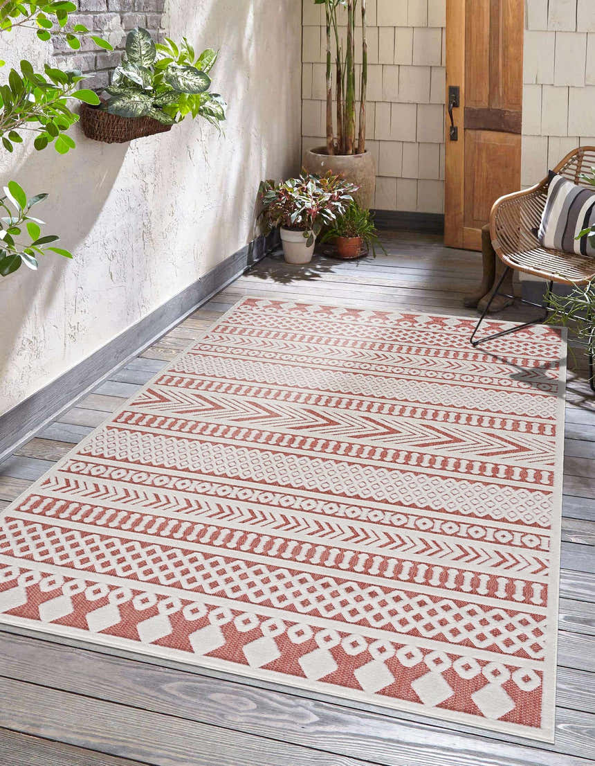 Outdoor patio scene with a Jove Orange outdoor rug, woven chair, wood door, and plants. Southwestern style. Roomscene-Rectangle