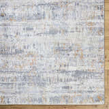 Close-up of the Guoda Area Rug, a contemporary design in driftwood, gray, and nutmeg hues. Machine woven texture. Corner