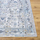 Close-up of the Irida Area Rug showing its traditional floral pattern in denim, gray, and nutmeg on a wood floor. Front
