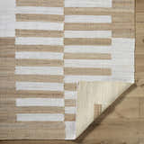 Close-up of the hand-woven Soren Area Rug. Jute rug features a geometric block pattern in ash, light silver, and tan. Fold