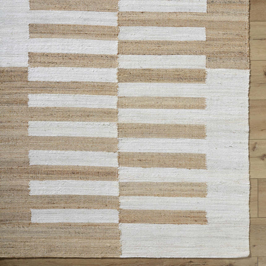 Close-up of the hand woven Soren Area Rug. Jute rug with ash, light silver, and tan horizontal stripes. Corner
