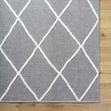 Close-up of Amani Gray Washable Rug with white geometric diamond pattern on a wood floor. Contemporary, farmhouse style. Corner
