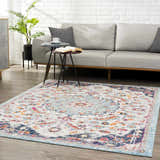 Living room scene with a Tigril Blue 2303 area rug, gray sofa, side tables, and plant against a white brick wall. Roomscene-Rectangle