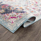 Close up of the Tigril Blue 2303 Area Rug showing beige, ivory, turquoise, pink, and navy floral pattern and texture. Fold