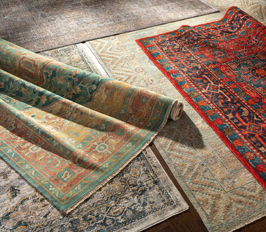 Close-up of rolled Managa Premium Rug, a hand-knotted wool rug with camel, beige, saffron, and sage tones. Traditional Persian style. Styleshot