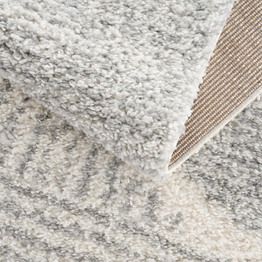 Close-up of the Trunding Plush Area Rug in Gray, showing the shag texture, geometric pattern, and woven backing. Fold