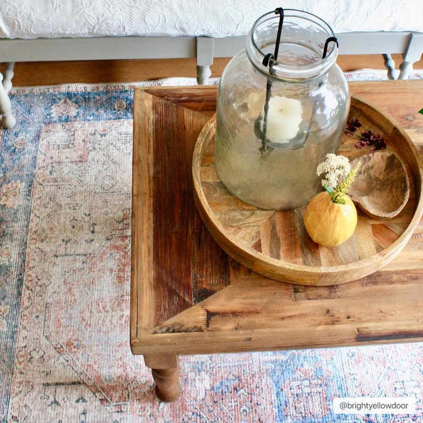 Living room scene with a Rosman Distressed Washable Area Rug in beige, blue, and brick red under a wooden coffee table. Roomscene-Rectangle