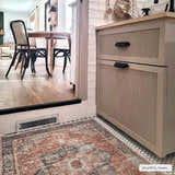 Farmhouse kitchen scene with a beige Rosman Distressed Washable Area Rug, cabinet, and black bistro chairs. Roomscene-Rectangle